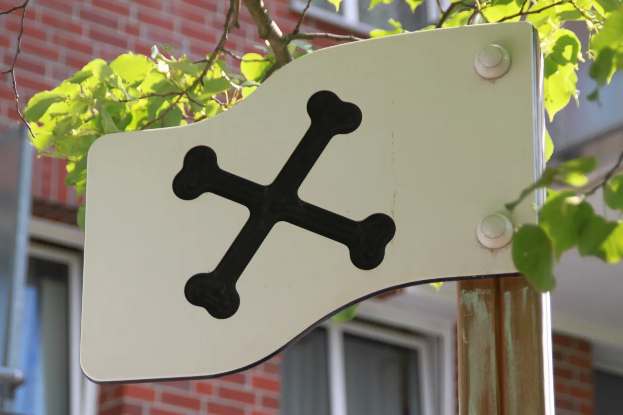 Weißes Schild mit schwarzem Knochensymbol am Zaun des Außengeländes.