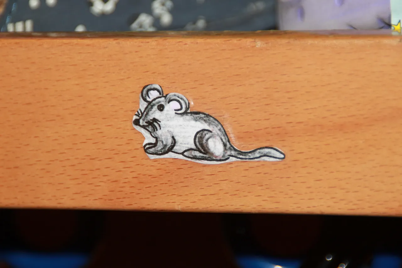 Aufkleber einer gezeichneten Maus auf einer Schrankkante.