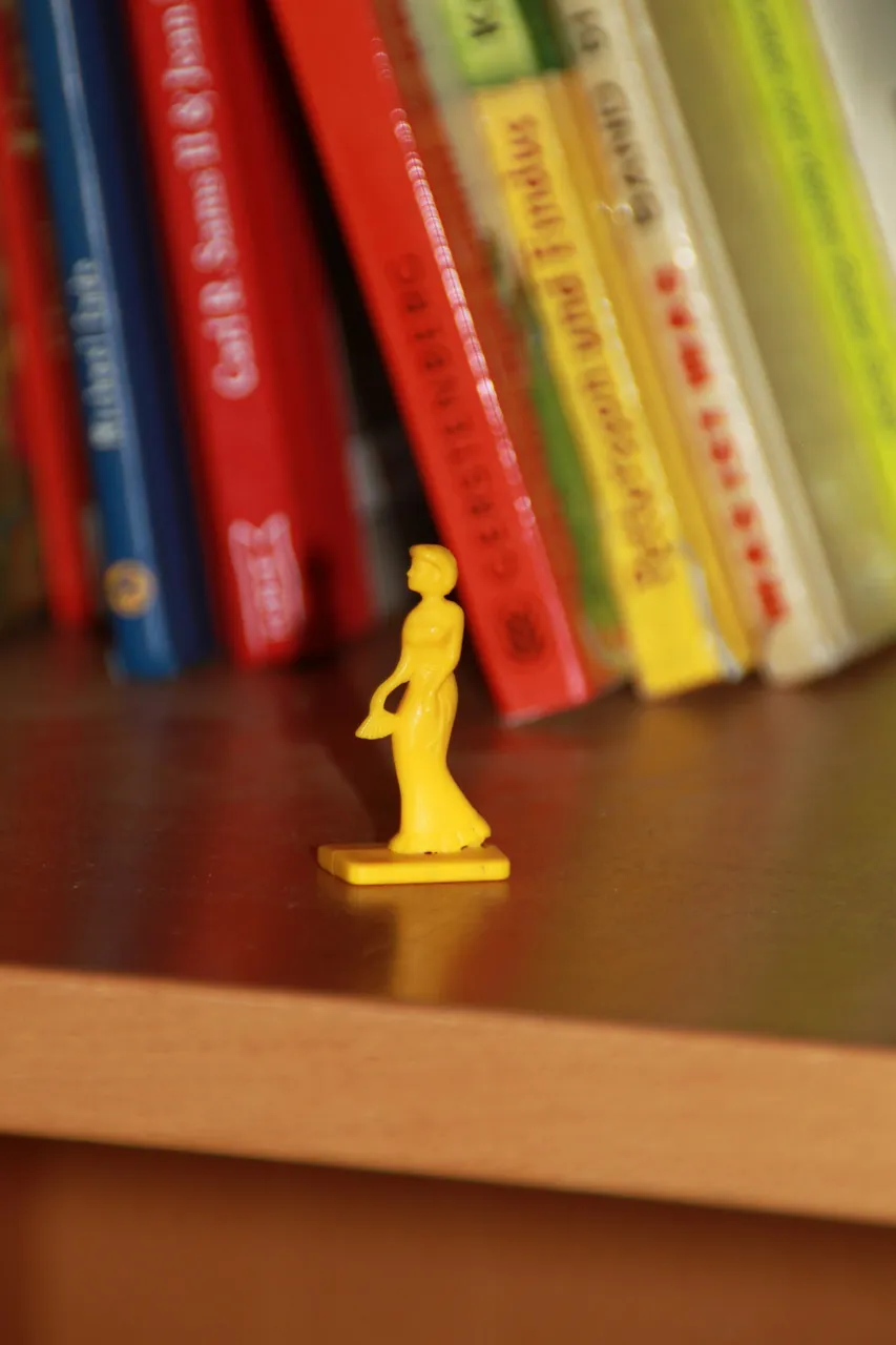 Bücherreihe in einem Regal, davor eine kleine gelbe Spielfigur.