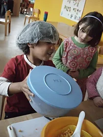 Zwei Kinder bereiten am Tisch gemeinsam Essen zu.